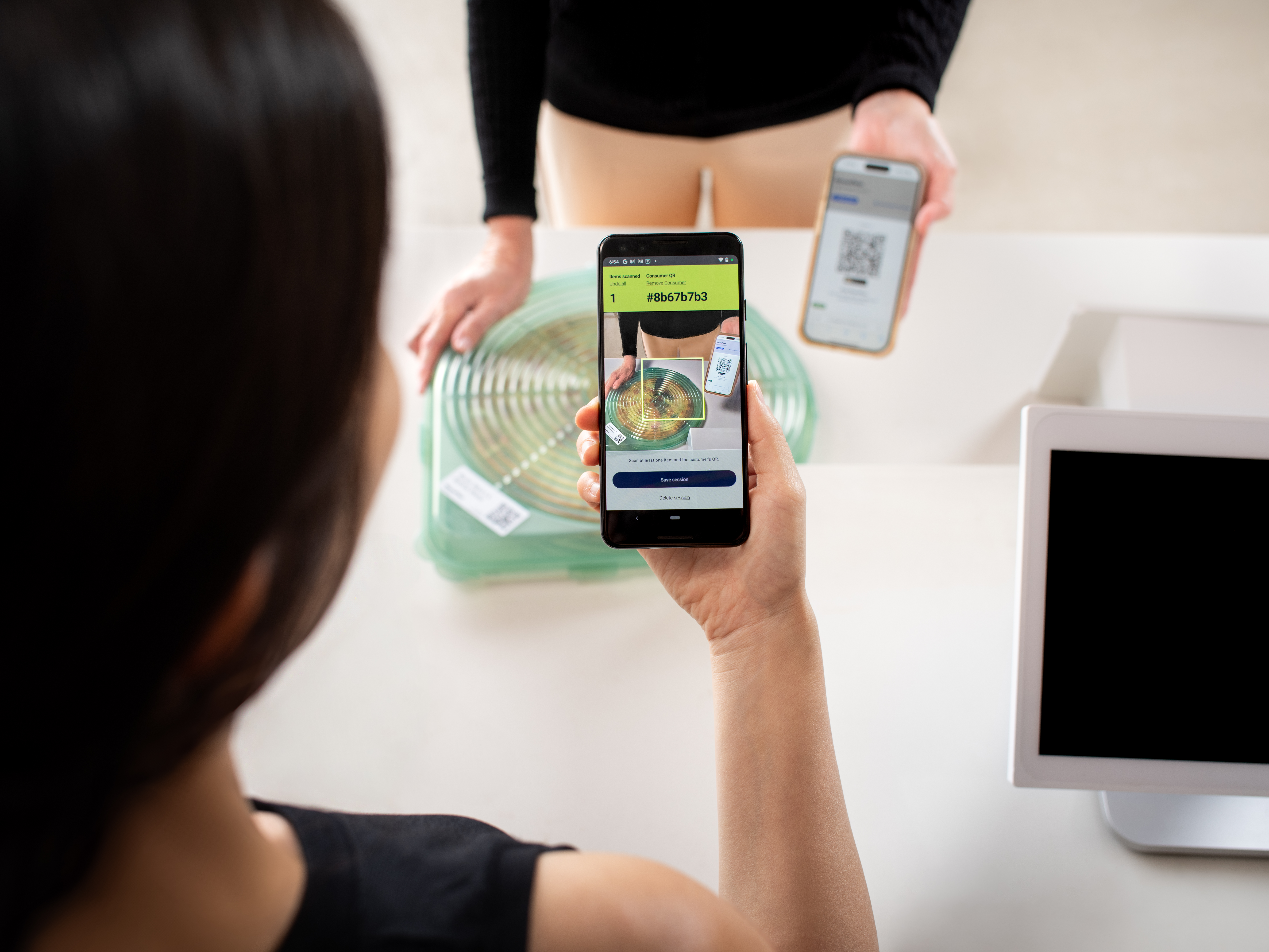 An operator scanning a reusable container and a customer's ReusePass QR code at checkout