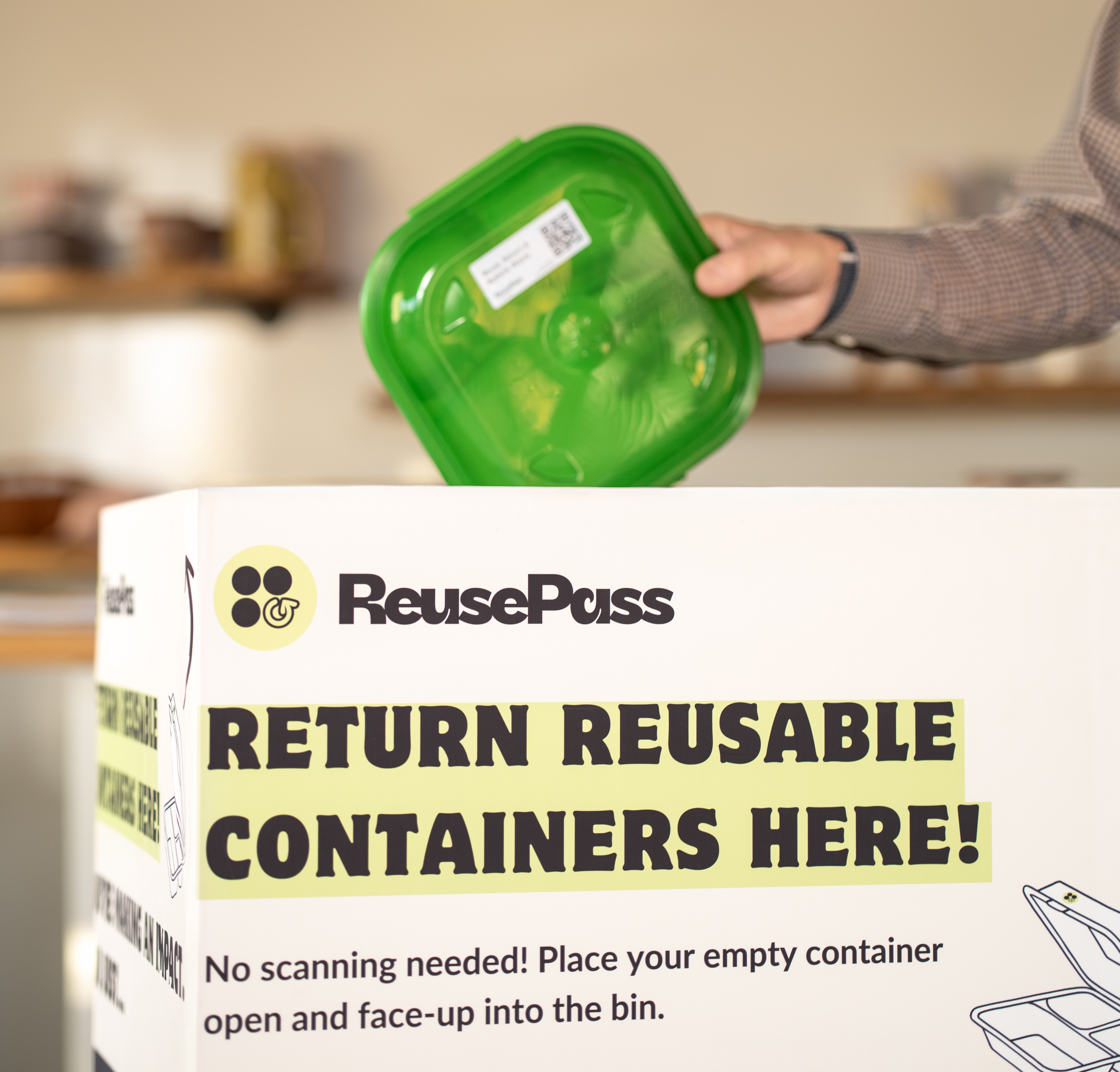 A customer placing an empty reusable container into a ReusePass return bin