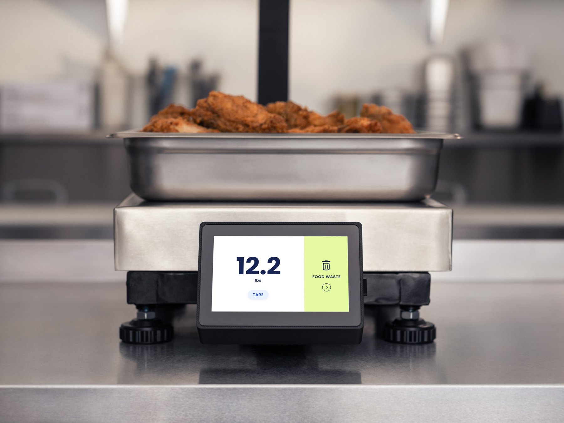 The MVP scale with a pan of fried chicken on it; its touchscreen shows 12.2 lbs and a single Food Waste button